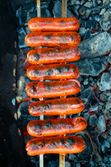 delicious sausages impaled on skewers are cooked on coals. food barb