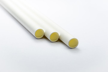 Close up white paper straws laying flat isolated on white background.