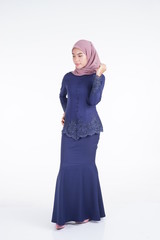 A beautiful Muslim female model wearing a dark blue modern kebaya with hijab, an Asian Muslim traditional dress isolated on white background. Eidul fitri fashion and lifestyle portrait concept.