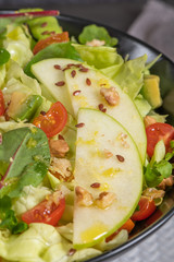 Salad. Spring vegetable salad. Fresh vegetable salad with tomatoes, apple, nuts, seeds and lemon. Olive oil pouring into bowl of salad