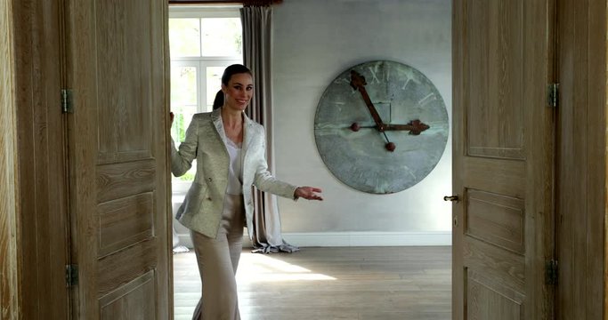 Beautiful woman opening door inviting to enter. Slow motion, static.