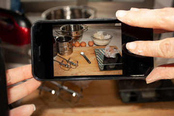  Chef taking pictures with his cell phone of the process of preparing food pots and ingredients