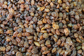 Many ripe raisins and dried fruits scattered on a table at street market