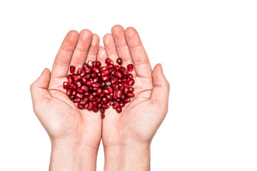 Ripe pomegranate seeds in hands on an isolated background.