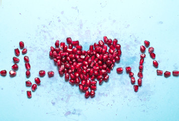 Conceptual photo of a healthy heart and a cardiogram made of pomegranate seeds. Proper diet.