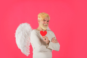 Obraz premium Cupid in valentine day. Male angel with red heart. Bearded man with angel wings holds paper heart. Blonde cupid with white angel wings. Happy Valentine Day. Cupid. Amour. Valentine cupid. February 14.