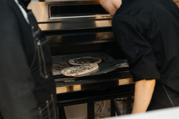The cook puts the pizza in the oven