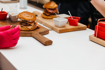 The cook is preparing a hamburger, on the background with the ingredients.  Delicious food. Menu, fast food