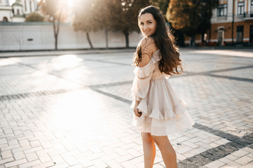 Beautiful young girl in a dress with long hair walks around the city