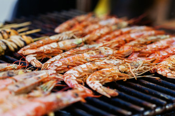 Grilled shrimps or barbecued shrimp cooking on charcoal stove. Street food festival