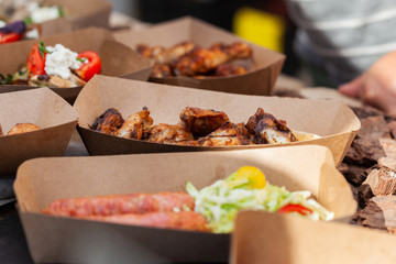 Grilled meat and vegetables in a paper container at the street food festival