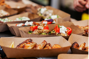 Grilled meat and vegetables in a paper container at the street food festival
