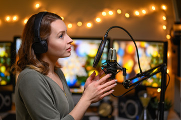 Girl blogger or radio host, working with a microphone, reading podcasts or news on the air. Homely...