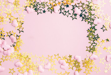 Golden stars glitter on pink background. Festive holiday pastel backdrop. Flat lay. Top view. Copy space