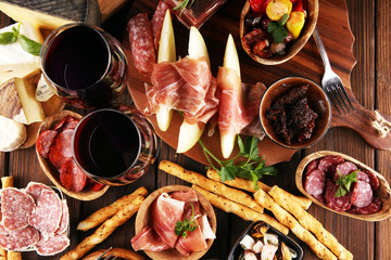 Fototapeta na wymiar Italian antipasti wine snacks set. Cheese variety, Mediterranean olives, seafood salad, Prosciutto di Parma, tomatoes, anchovy and wine in glasses