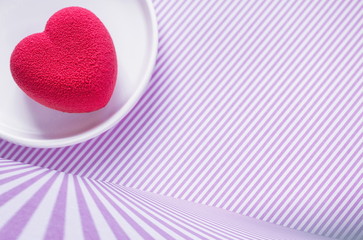 Valentines day concept. Pink velvet heart in a white porcelain plate on a pink checkered surface