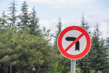 Traffic Sign Do not turn Left with blur background oh pine tree and cloudy sky