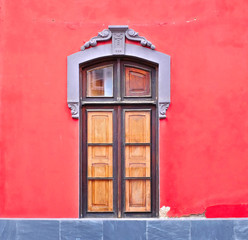 A joyful wooden window frame in a bright red wall, a lovely example of classic European style architecture.