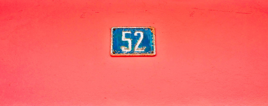Number 52, fifty-two, blue plate on vibrant pink background.
