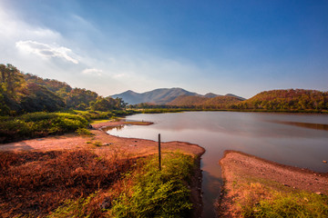 The blurred panoramic nature background of sunlight hitting the lake's surface, grass and wind blowing all the time along the large mountains, ecological beauty and fresh air.