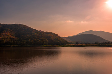 The blurred panoramic nature background of sunlight hitting the lake's surface, grass and wind blowing all the time along the large mountains, ecological beauty and fresh air.
