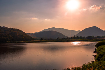 The blurred panoramic nature background of sunlight hitting the lake's surface, grass and wind blowing all the time along the large mountains, ecological beauty and fresh air.
