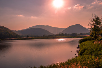 The blurred panoramic nature background of sunlight hitting the lake's surface, grass and wind blowing all the time along the large mountains, ecological beauty and fresh air.