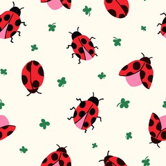 Allover seamless repeat pattern with cute hand-drawn ladybugs of different shapes flying on a cream ground with ditsy green clover leaves tossed.