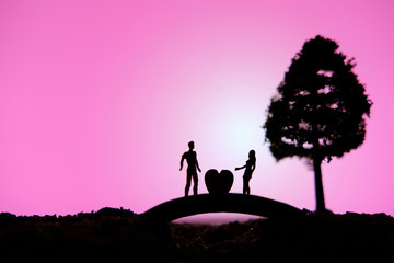 miniature people / toy photography - conceptual valentine holiday illustration. A man proposing a girl silhouette above the bridge holding a heart 