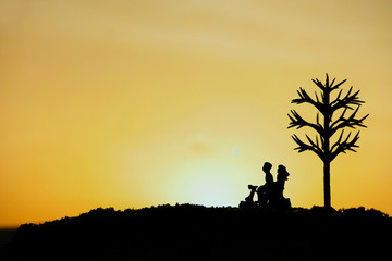 Fototapeta na wymiar miniature people / toy photography - conceptual valentine holiday illustration. A couple silhouette riding a scooter at the sand beach with dried tree