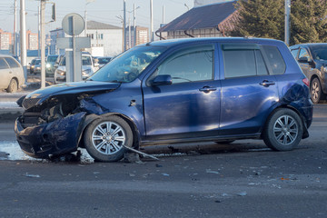 A traffic accident on a city street, a car with a broken front.
