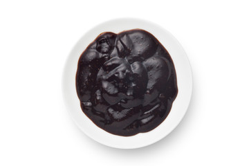 Black pepper sauce in a ceramics plate isolated on white background. Top view.
