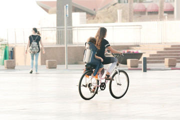 Older sister rides brother on a bicycle with a child seat