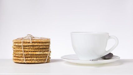 White Cup and saucer and homemade waffles on the table on a light background.