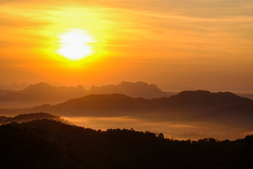 Nature landscape background beautiful view of the morning fog filling the valleys of smooth hills mountain range layer yellow forest sunrise and sunset in mountains with orange sky