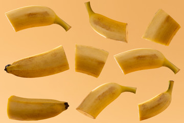 Bananas of various shapes are suspended in front of a yellow background.