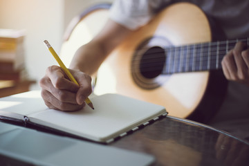 Fototapeta na wymiar artist songwriter thinking writing notes,lyrics in book at studio.man playing live acoustic guitar relax chill.concept for musician creative.composer work process.people relaxing time with instrument