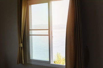 window view sea beach and mountains in the bed at bedroom morning and sunlight - window glass with drapery