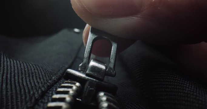 Close up of fingers zipping up a black jacket. Shot in 4K RAW on a cinema camera.