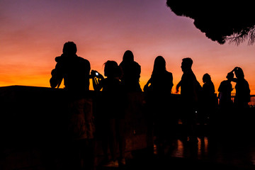 Silhouettes of people watchin sunset in Lisbon from Miradouro da Graca viewpoint, Portugal