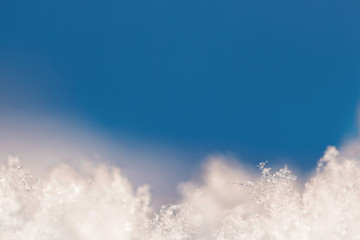Background from crystal clear real snowflakes in blue shades in macro with copy space for your text. Christmas and New Year background frame with a border of natural ice snowflakes close-up.