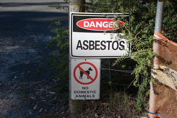 Fototapeta premium A warning sign Danger Asbestos on a fence at site rehabilitated post asbestos contamination
