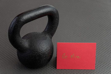 Naklejka na ściany i meble Holiday fitness, black kettlebell, with a red valentine card, on a black gym floor