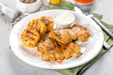 Chicken with corn, sauce on a white plate