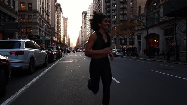 Beautiful young fit hispanic woman jogs runs on New York city street. Slow motion. Concept of urban healthy active lifestyle, summer exercise in NYC, healthy living, american sexy millennial.