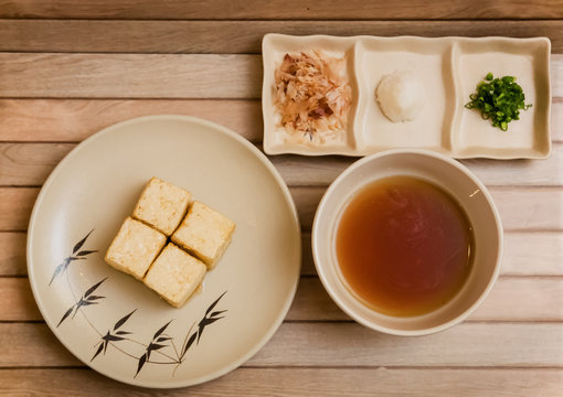 preparation of age dashi tofu. It is crispy deep fried tofu served with dashi sauce, green onion, grated radish and bonito flakes.