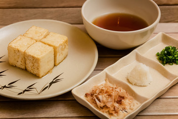 preparation of age dashi tofu. It is crispy deep fried tofu served with dashi sauce, green onion, grated radish and bonito flakes.