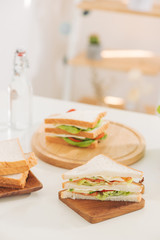 Sandwich on cutting board on the table in the bright kitchen. Lunch. Sandwich with lettuce. Healthy eating concept.