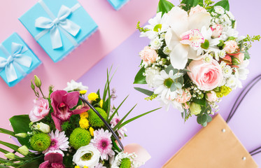 Flower bouquet with blue gift boxes on colorful background flat lay top view