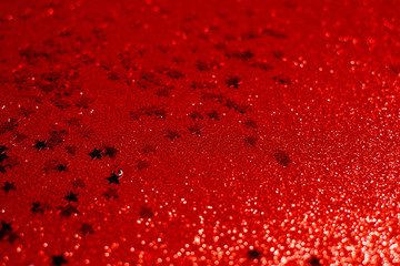 Holiday background with little red stars on red glittering background. Copyspace top horizontal view